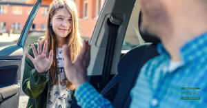 young girl waving goodbye to adult at school drop-off